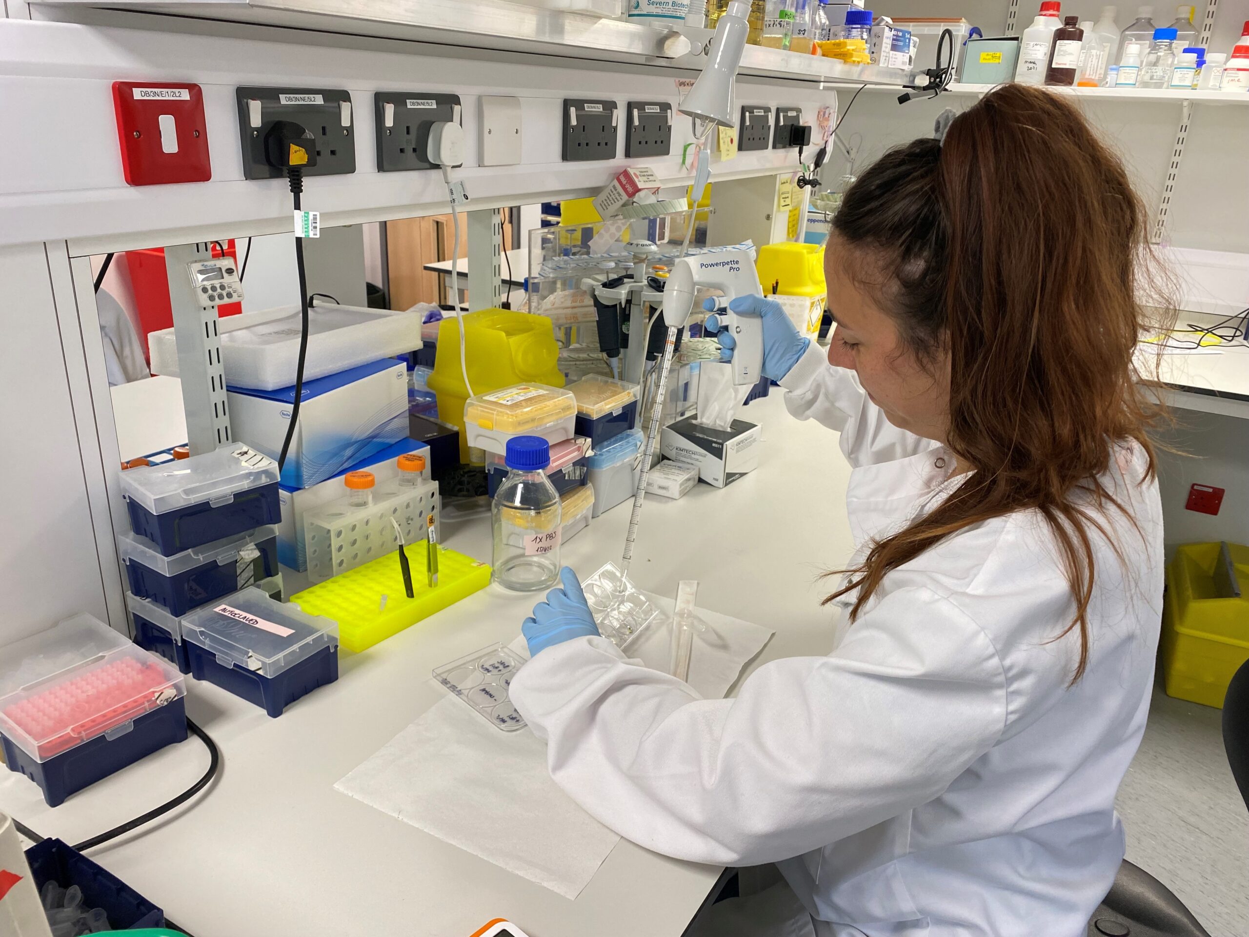 Dr Audrey Lumeau sitting at the laboratory bench pippetting some liquid.