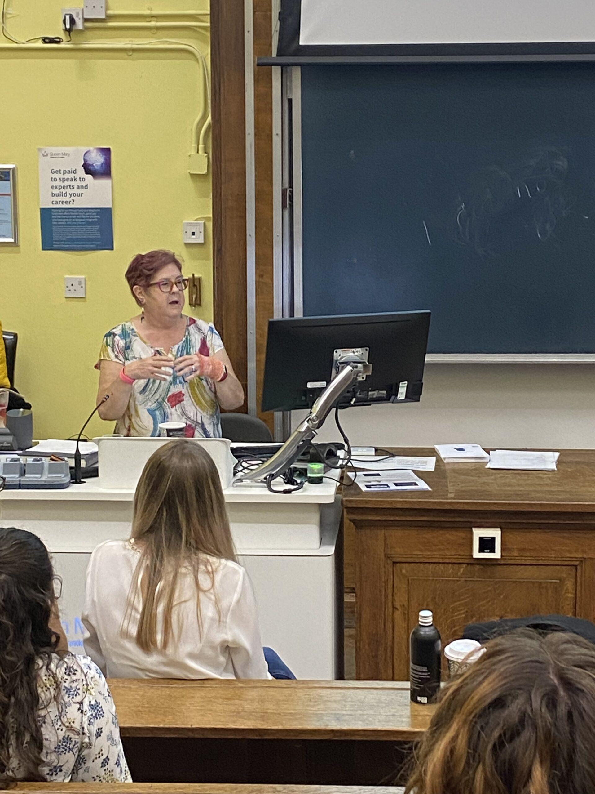 Dr Adrienne Morgan standing at the front of a lecture theatre delivering a presentation.